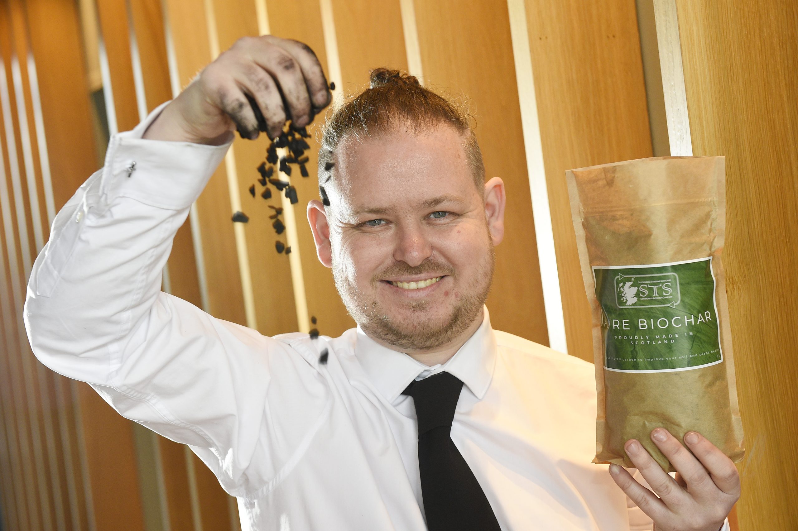 Sean Kerr of Sustainable Thinking Scotland sprinkles some biochar out of a packet