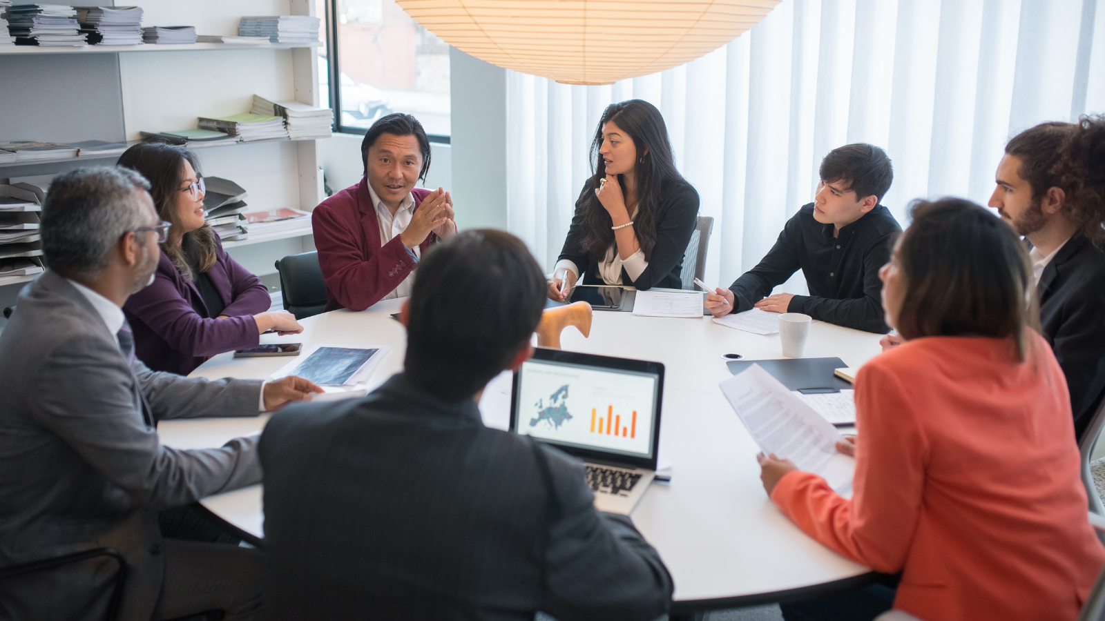 A group of people sitting around a Board table